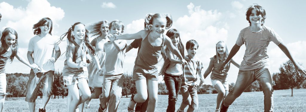 eine Gruppe von Kindern läuft enthusiastisch über eine Wiese